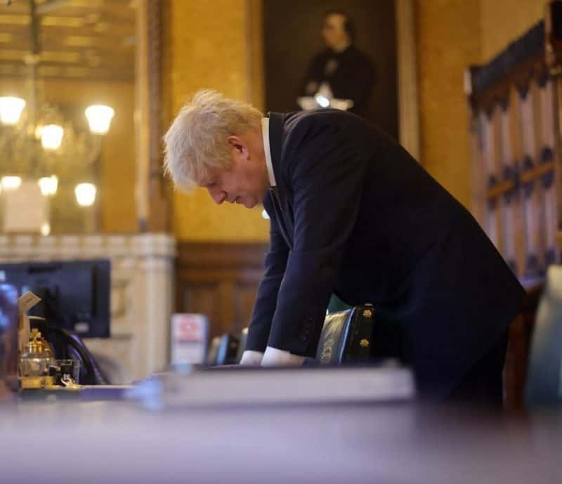 Boris Johnson bends down at a desk in parliament, embodying the principle there is more to life.