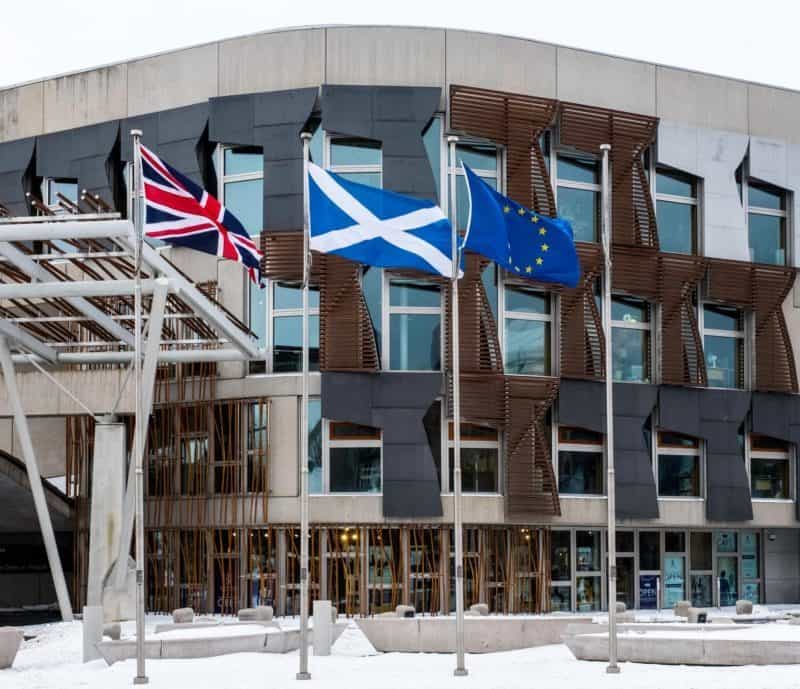 Scottish parliament building with flags flying in the snow, showcasing Scotland.