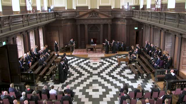 A group of people are sitting in a large room, engaging in conflict resolution.