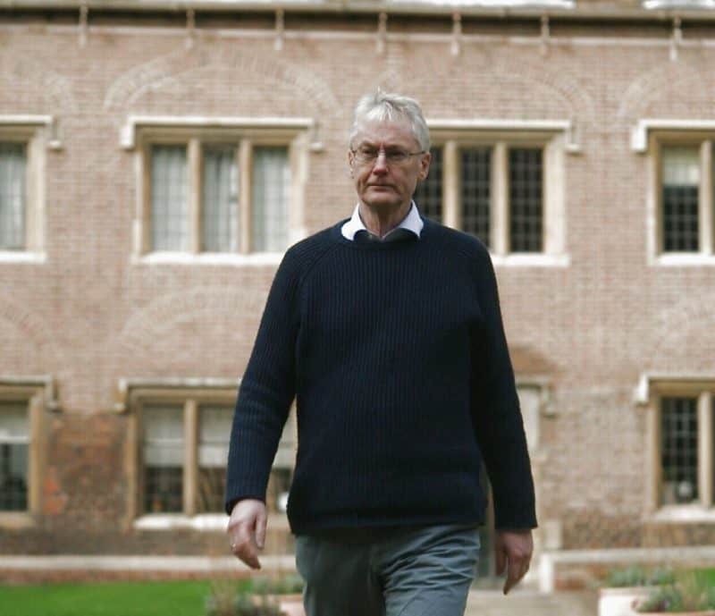 Mike Hulme walking in front of a brick building.