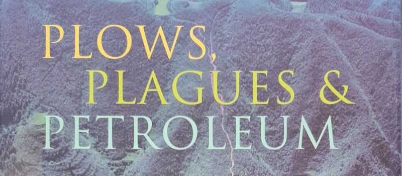 Cover of "Plows, Plagues & Petroleum," a 2005 Book of the Year and acclaimed climate book, featuring an aerial photo of green, terraced hills in the background.